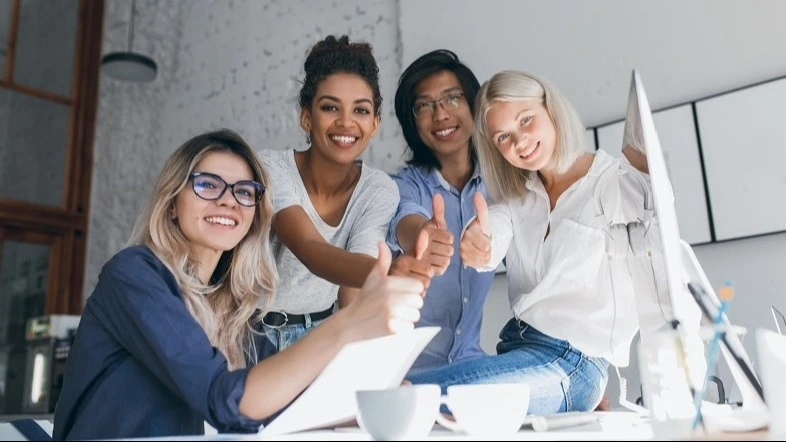 Vier lachende Auszubildende zeigen Daumen hoch am Schreibtisch – Online-Kurs Prüfungstraining ZFA Zwischenprüfung | Spitta Akademie